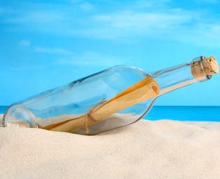 Photo of a paper inside a bottle on the beach sand